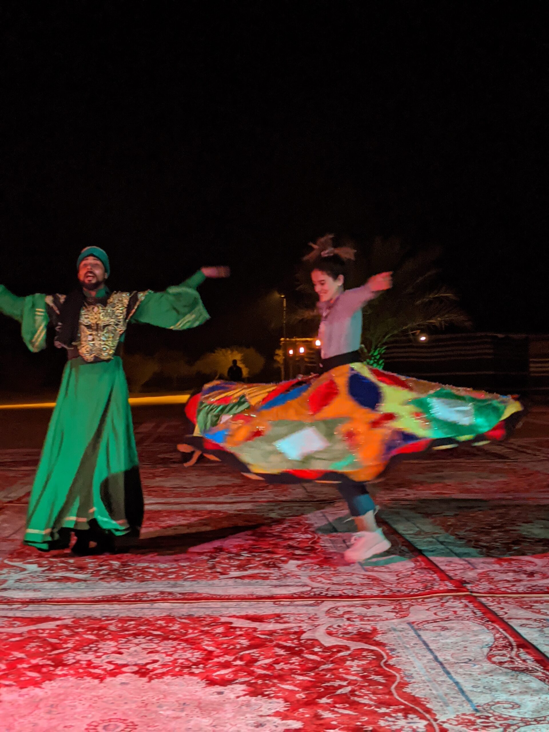 A whirling dervish performer in a brightly coloured spinning skirt at the desert encampment