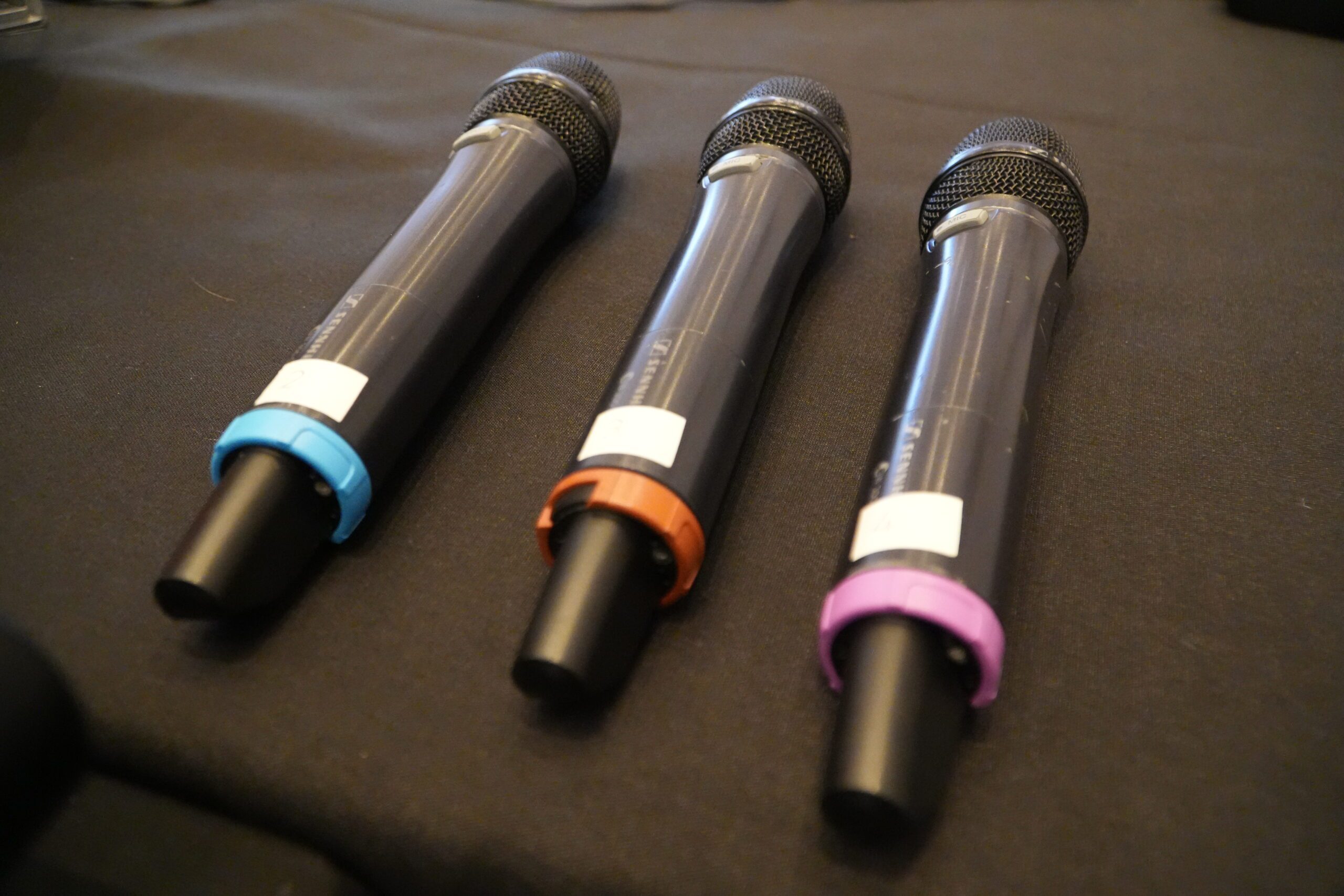 Colour-coded Sennheiser wireless handheld microphones ready for presenters